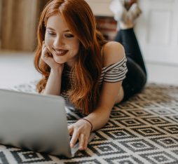 Une femme regarde son écran en souriant