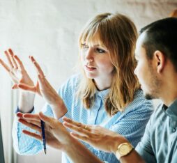 Deux professionnels analysent ensemble un écran dans un bureau lumineux, illustrant la supervision humaine et la coordination dans un projet technologique.